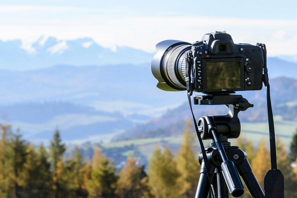 A camera mounted on a tripod, set to take a professional photo of the landscape ahead.