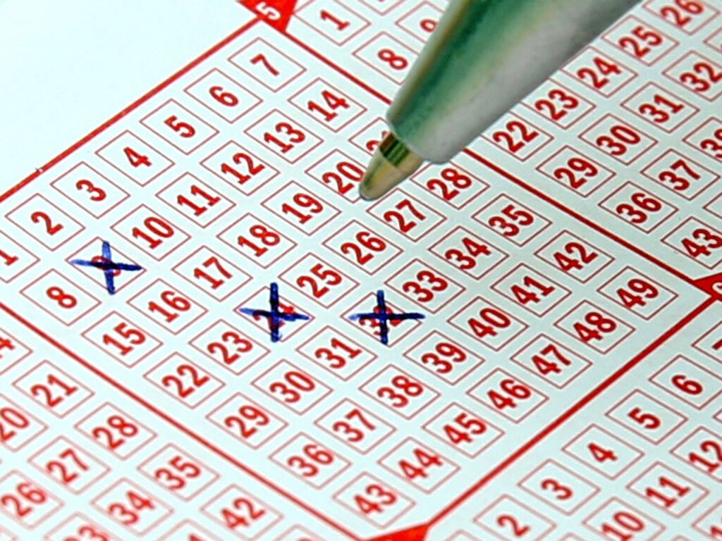 A close up photo of a pen tip checking number boxes of a Lotto grid.